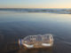 A plastic bottle littering a beach in Melbourne, Australia. Sunset and horizon line in the background.